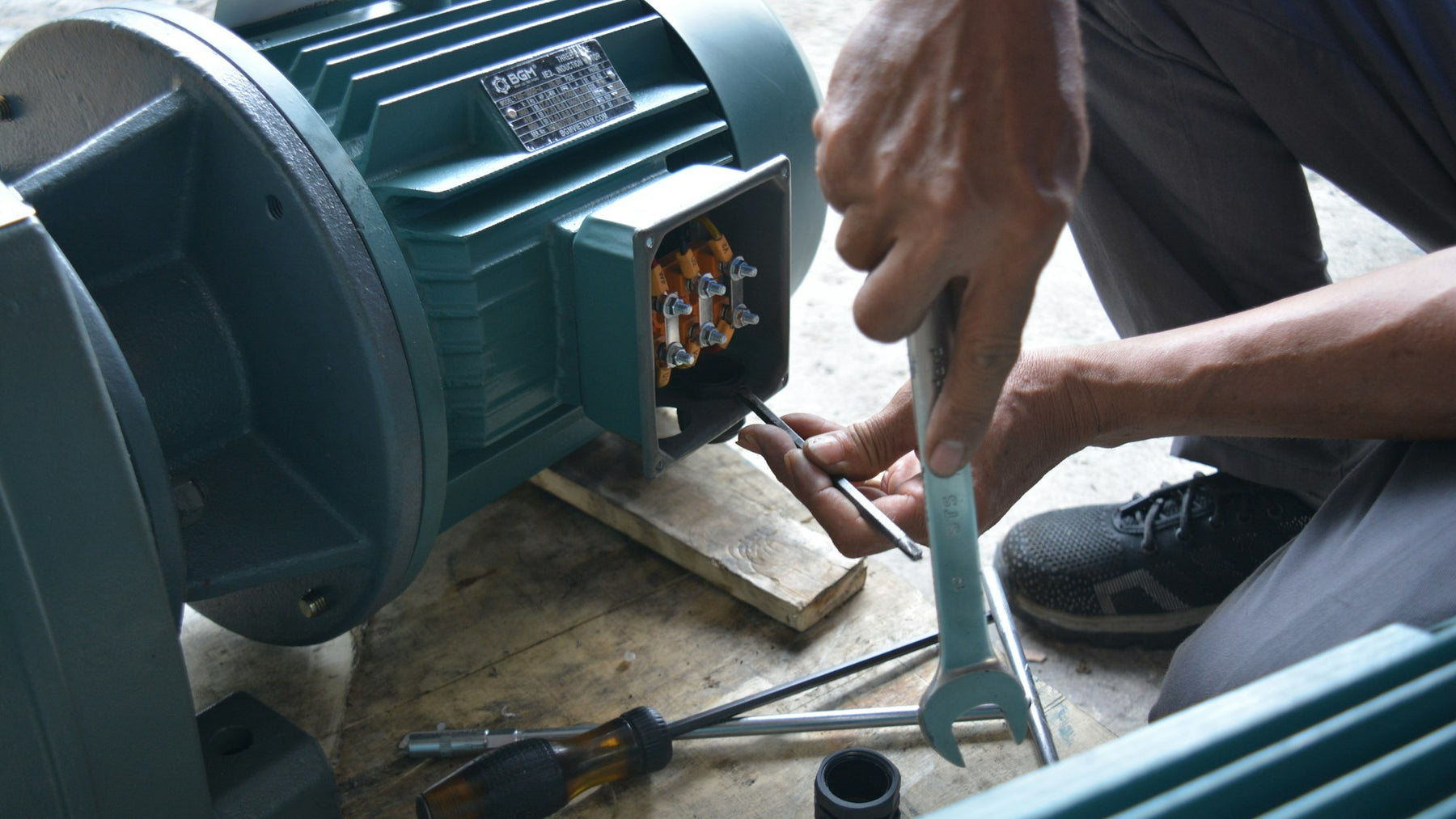 Technician testing an electric motor with a wrench