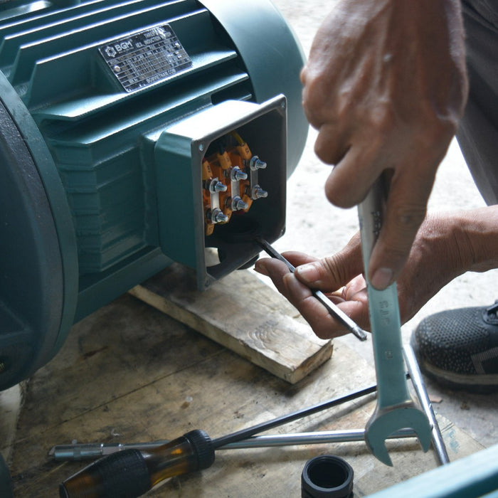Technician testing an electric motor with a wrench