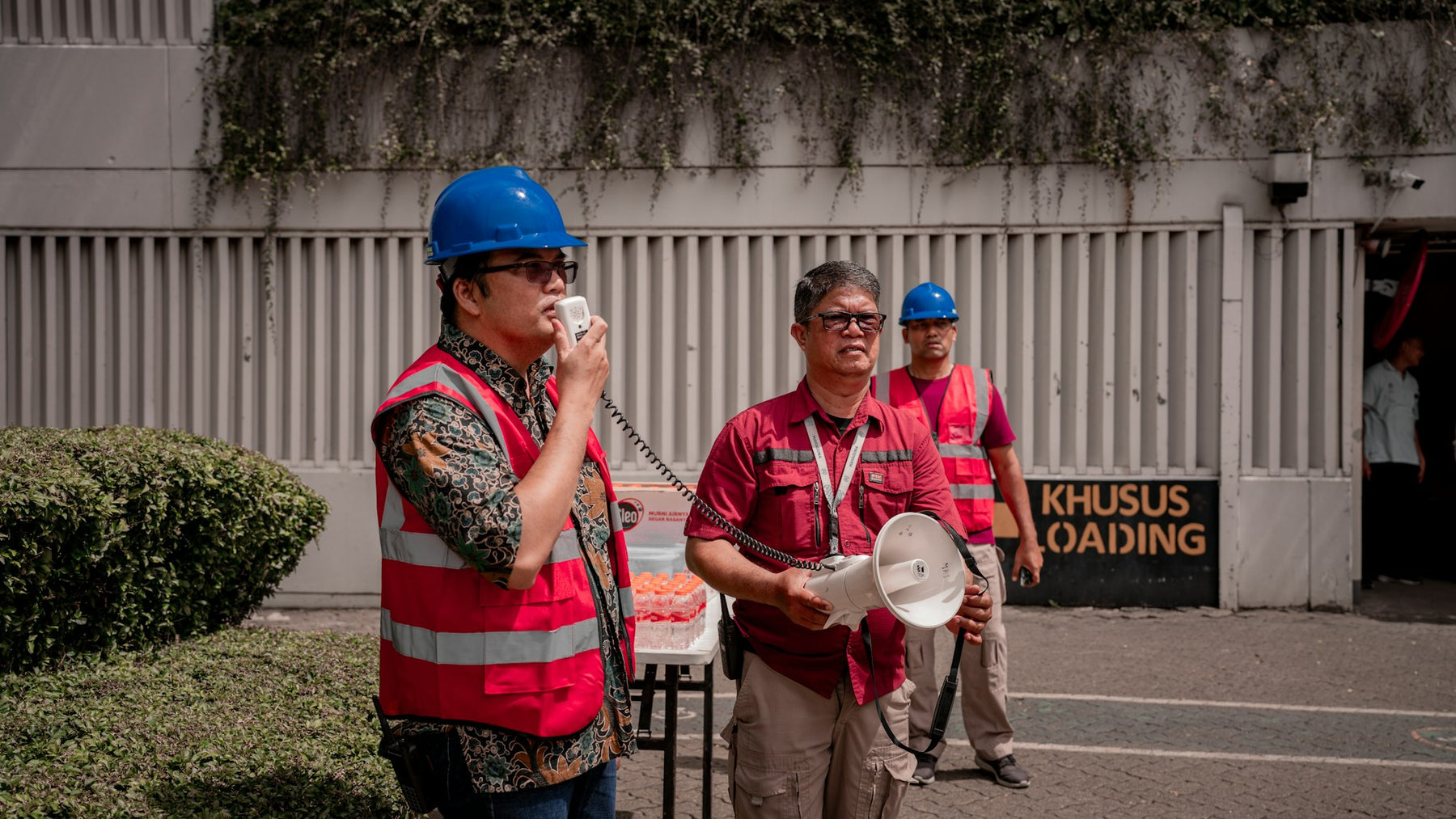 Workers in hard hats and safety vests talking at a job site
