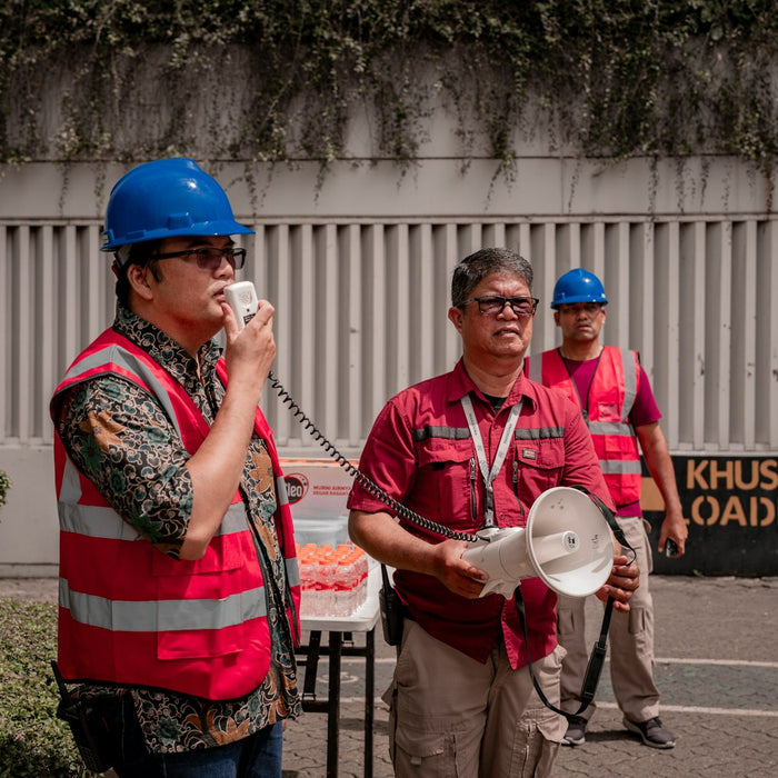 Workers in hard hats and safety vests talking at a job site